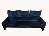 black velvet sofa with four pillows on it against a white background