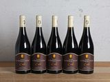 six bottles of wine are lined up on a wooden table