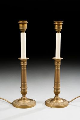 pair of antique brass candlesticks with white candles on them