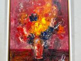 un tableau accroché au mur d'une pièce où se trouve un vase de fleurs