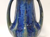 a blue vase with a handle on a white surface
