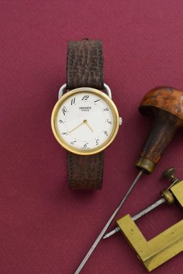 une montre et un jeu d'outils posés sur une surface rouge