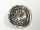 an antique silver button with a lion on it on a white surface