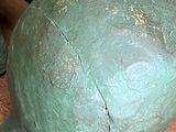 a green sculpture of a man ' s head on a wooden table