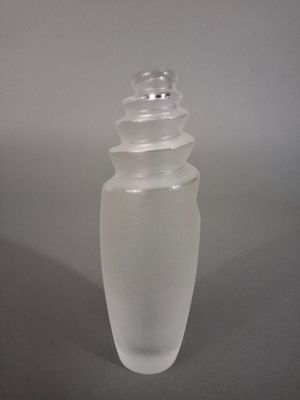 une bouteille en verre transparent avec un bouchon argenté posée sur une table