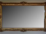 a gold framed mirror hanging on the wall above a sink