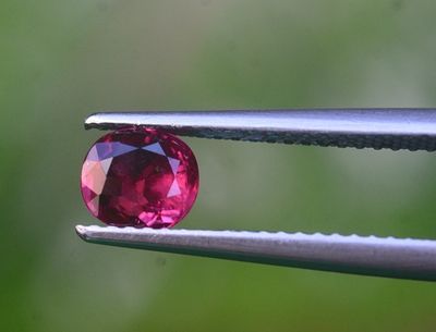 un gros plan d'un diamant rose tenu par une paire de pinces