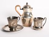 un service à thé en argent composé d'une tasse et d'une soucoupe posées sur une assiette