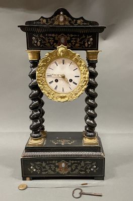a black and gold clock on a stand with a key