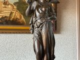 une statue représentant une femme tenant un oiseau, posée sur une table