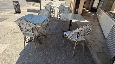 tables and chairs on the sidewalk outside of a restaurant