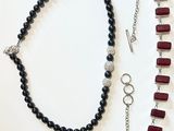 two necklaces and a bracelet with red beads on a white surface