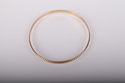 gros plan d'un bracelet en or sur une surface blanche