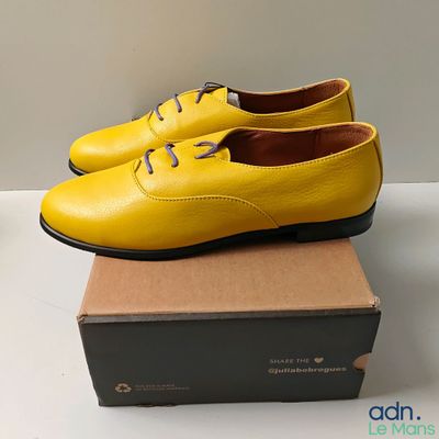 une paire de chaussures jaunes posée sur une boîte, elle-même posée sur une table