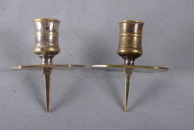 une paire de bougeoirs anciens en laiton posés sur un socle, sur fond blanc