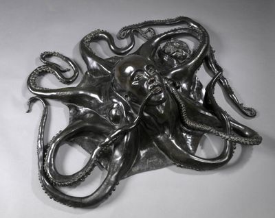 une photo d'une sculpture métallique représentant une pieuvre posée sur une surface blanche