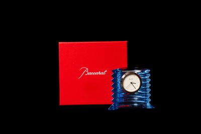 une petite horloge posée à côté d'une boîte rouge sur une table