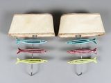 trois crochets en forme de poisson sont fixés au mur, à côté d'une lampe