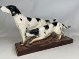 une statue représentant un chien et un chat, posée sur un socle en bois
