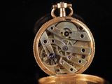 a close up of a gold pocket watch with a black background