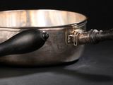 une casserole en argent et une cuillère en argent posées sur une table noire