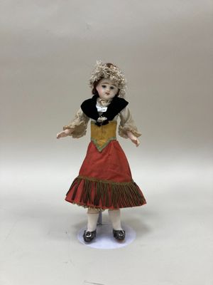 poupée en porcelaine représentant une jeune fille vêtue d'une robe rouge à col noir