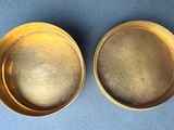 a pair of brass bowls sitting on top of a blue surface