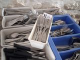several trays of forks and spoons sitting on top of a wooden table