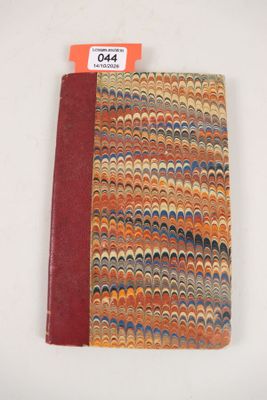 un petit cahier à la couverture rouge posé sur une table blanche