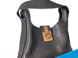un sac à main noir et une serviette bleue posés sur une surface blanche