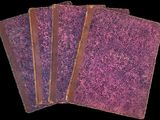 trois livres violets à la couverture marron sont empilés les uns sur les autres