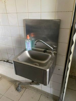 un lavabo dans des toilettes publiques, avec une bouteille d'eau à l'intérieur
