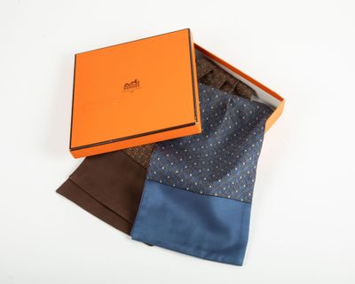 an orange box with three different colored ties in it on a white surface