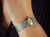 someone is wearing a watch with a yellow face and a chain bracelet