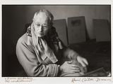 photographie en noir et blanc d'une vieille femme assise à une table