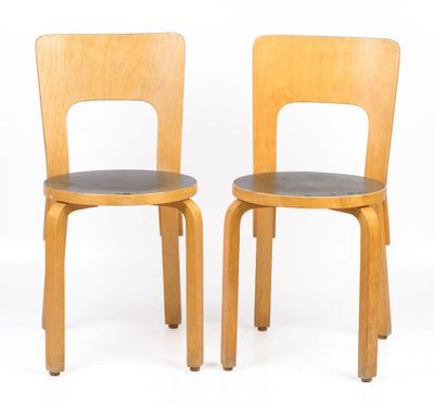 pair of wooden chairs with black leather seats against a white background