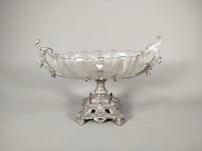 un plat ancien en argent, orné d'un motif décoratif, posé sur un socle