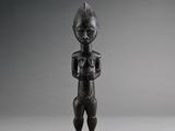 une vieille statue en bois d'un homme avec un chapeau sur la tête