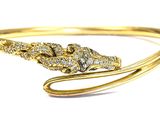 a close up of a gold bracelet with a snake on it