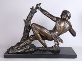 bronze statue of a man sitting on a tree branch