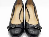 une paire de chaussures en cuir noir avec une boucle métallique au talon