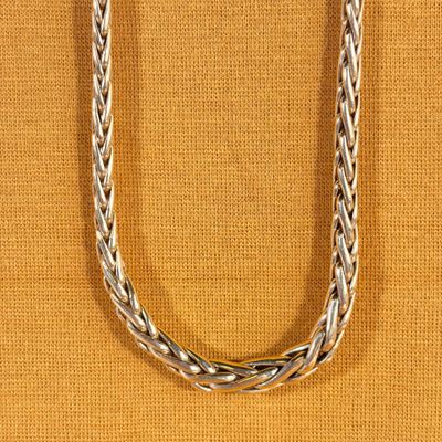 a close up of a silver necklace on a brown background