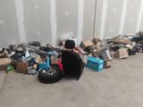 un chat assis par terre à côté d'un tas de vieilleries