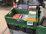 a pile of books in a green crate on the sidewalk
