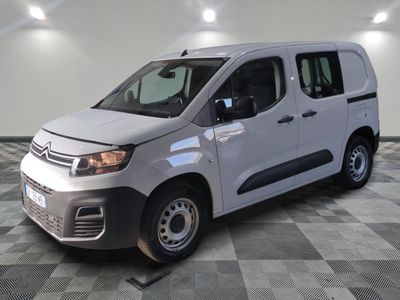 La camionnette blanche est garée dans le garage, sur un sol à carreaux.