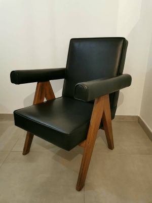 un fauteuil en cuir noir avec des pieds en bois dans une pièce