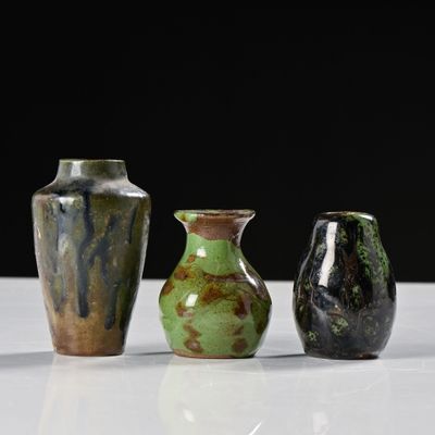 trois vases posés sur une table blanche, sur fond noir