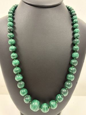 a green beaded necklace on a mannequin display