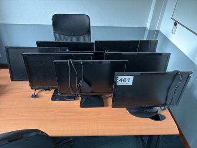 four computer monitors sitting on a desk in an office