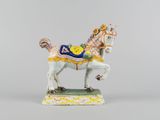figurine of a white horse with a blue saddle on a green base